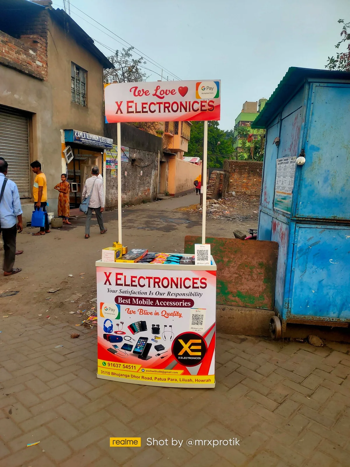 X ELECTRONICES early beginning beside Liluah Railway Station Road in Howrah with a small roadside promotional and accessories setup